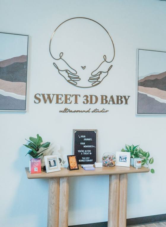 Sweet 3D Baby reception area with the studio sign, framed ultrasound prints and a candy jar.